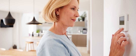 A woman looking at a thermostat.